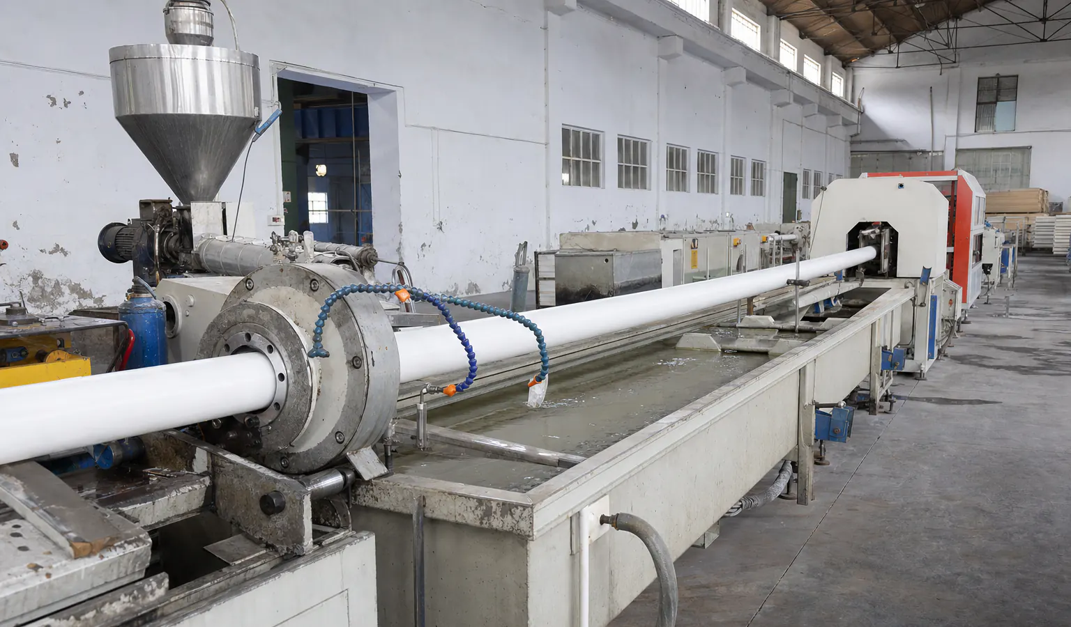 خط بثق حقيقي لأنابيب PVC يوضح القالب وأحواض التبريد ووحدة السحب ومعدات القص